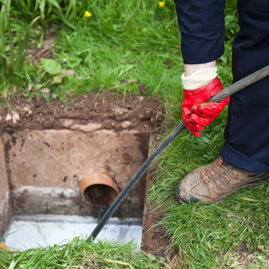 Photo montrant des mains et pieds équipés de gants et bottes utilisant un deboucheur assainisseur dans un pack chemisage de canalisation